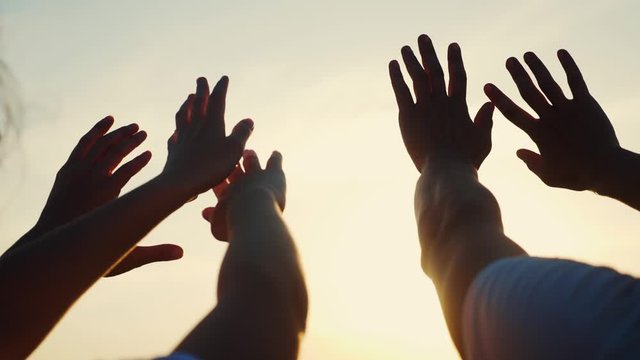 happy family people group pull hands to the sun teamwork. silhouette people party dancing recreation holiday. people at a music concert pull their hands up. religion sunlight concept lifestyle