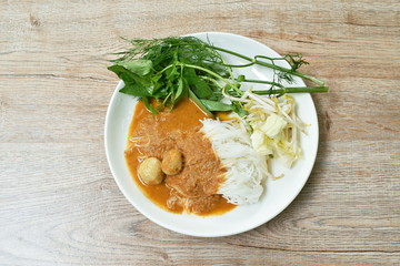 rice noodles dressing with meat ball fish coconut milk curry sauce and fresh vegetable on plate