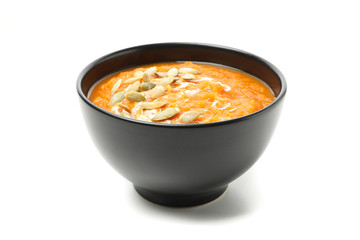 Bowl of pumpkin soup with seeds isolated on white background