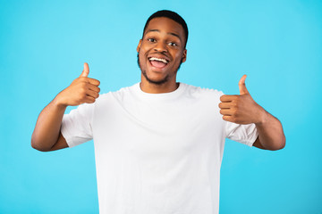 Black Millennial Guy Gesturing Thumbs-Up With Both Hands, Blue Background