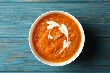 Bowl of pumpkin puree on wooden background, top view