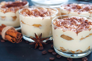 exquisite tiramisu in glasses decorated with cocoa powder on a dark background