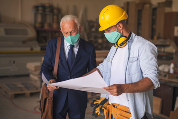 Two man going through business papers wearing face masks