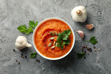 Composition with bowl of pumpkin soup on gray background, top view