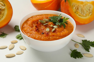 Composition with bowl of pumpkin soup on white background, close up