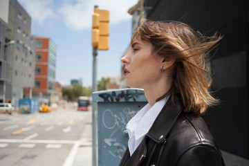 Close-up portrait of young elegant woman, messy hair and red lips looking aside. Fashion street shot.