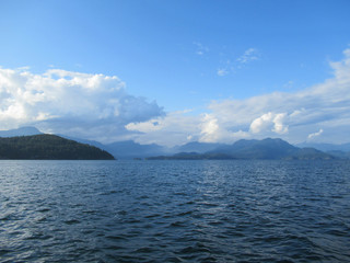 Beautiful landscape with sea, mountains and white clouds on blue sky near Vancouver.