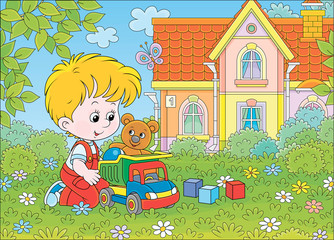 Little boy playing with a toy truck, a funny teddy bear and color cubes among flowers on green grass of a lawn on a summer day, vector cartoon illustration © Alexey Bannykh