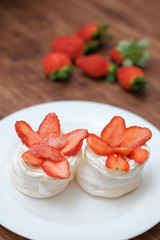 Obraz na płótnie Canvas Mini pavlovas with whipped cream and fresh strawberry