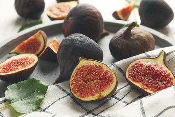 Tray with fig, leaves and towel on wooden background, close up