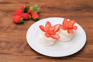 Mini pavlovas with whipped cream and fresh strawberry