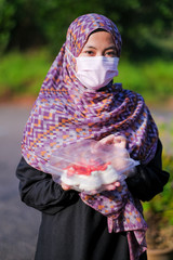 Young girl in hijab and face mask is holding delicious homemade Pavlova cake