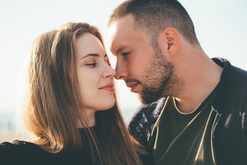 Happy couple in love. Beautiful man and woman look at each other tenderly, close-up portrait. Two together, young family on sunny day. Brunette and brown hair female