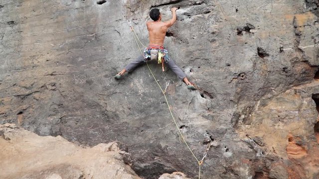 Muscular Man Climbing Up On Rocky Wall