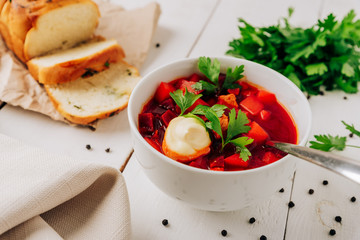 Borscht with fresh bread on a natural wooden background. Red beetroot soup with fresh bread