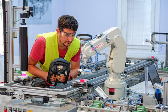 Man is programming robot arm with control panel which is integrated on smart factory production line. industry 4.0 automation line which is equipped with sensors and robotic arm. Selective Focus.