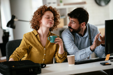 Colleagues in office. Businesswoman and businessman discussing work while drinking coffee.