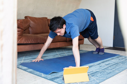 Man exercising at home in front of laptop