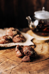 Teapot with black tea and homemade chocolate cookies on a brown natural wooden background