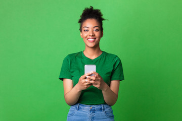 Smiling afro girl using smart phone at studio