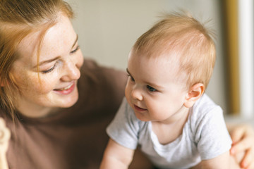 Mom hugs with her newborn baby in bed. Nine month old baby. Baby care, tenderness, motherhood