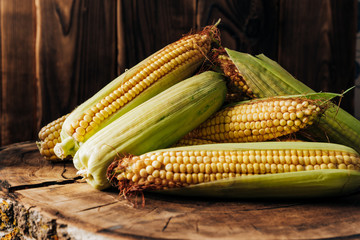 Fresh corn on the cob on a brown natural wood background close up