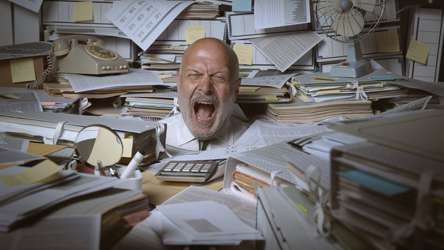 Stressed businessman buried under a lot of paperwork