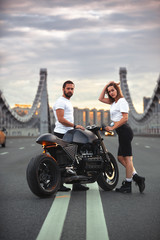 Love and romantic concept. Beautiful couple on motorcycle stands opposite each other in the middle of the road on the bridge, on double solid
