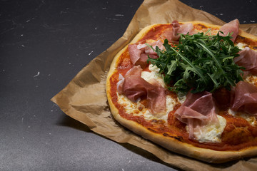 Homemade pizza with arugula, parma ham and mozzarella                               