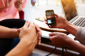 Closeup image of two person are watching video in internet via cellphone, while they are sitting in hipster coffee shop interior. Closely of woman`s hand is holding mobile phone with copy space screen