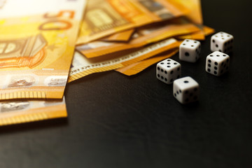 Gaming dice and money on black background