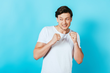 Scared man with hands in fists looking away on blue background