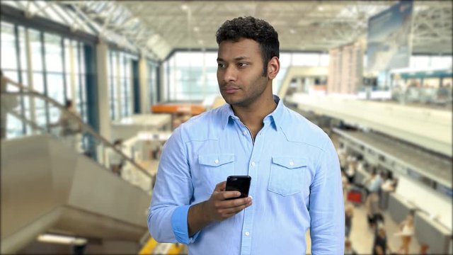 Confident man taking photo with smartphone. Handsome Indian man taking picture with mobile phone. Underground subway background with moving escalator.