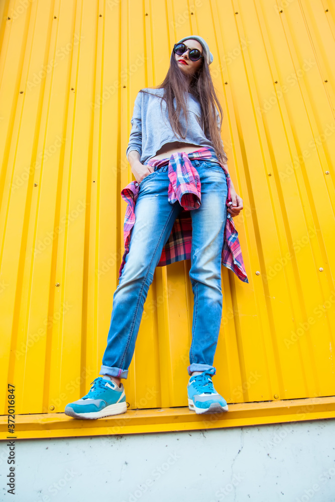 Wall mural Beautiful Trendy teen Girl over Yellow Wall