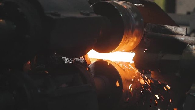 Moving on a hot metal ribbon, production process at a metal rolling plant, rolling metal in production ball production phase, rolling through sparkling metal rollers