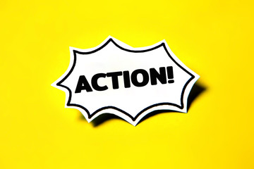 Action speech bubble on white paper isolated on yellow paper background with drop shadow.