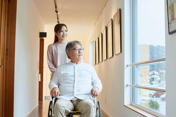 車椅子のシニアの男性を介助する若い女性