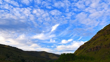 Green mountain with blue sky with strange shaped clouds. Cidacos Valley.