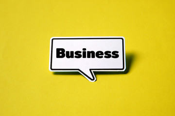 Business speech bubble on white paper isolated on yellow paper background with drop shadow.