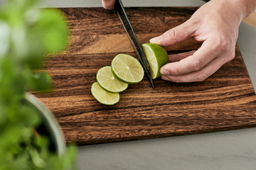 Mann, der eine Limette auf einem Holzbrett in Scheiben schneidet