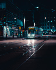 Tram an Haltestelle bei Nacht