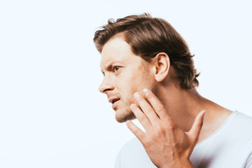 Fototapeta premium Concentrated man looking away while touching cheek isolated on white