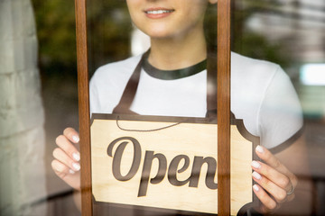 Obraz premium Open sign on the glass with reflection of street cafe or restaurant. Coronavirus pandemic new safety rules. Opening after quarantine time. Small business recovery after insulation. Close up.
