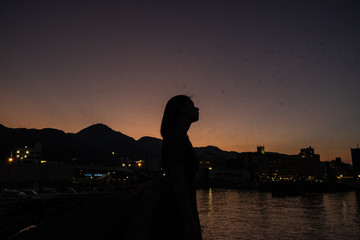 silhouette of a woman walking on a bridge at sunset
