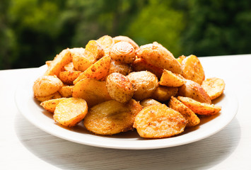Baked crispy potato on white plate on the windowsill. Side view. Close-up.