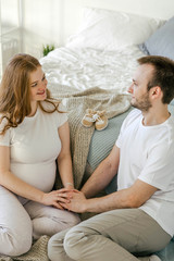 Family waiting for the baby. Husband and pregnant wife in a bright interior hug and smile