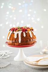 Traditional Christmas cake with fruits, nuts and white glazeon a light background with Christmas decorations. Copy space.