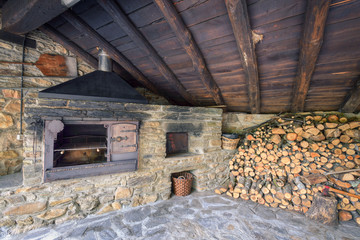 Grill and stone oven next to a woodshed