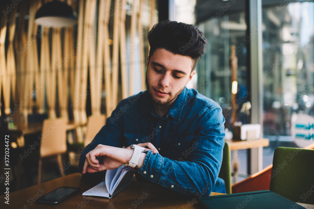 Poster pensive young man checking notification on modern wearable smartwatch reading message on touch scree