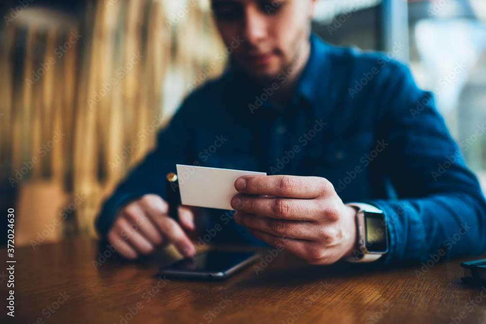 Poster selective focus on blank visit card in hands of hipster guy using email address for sending message 